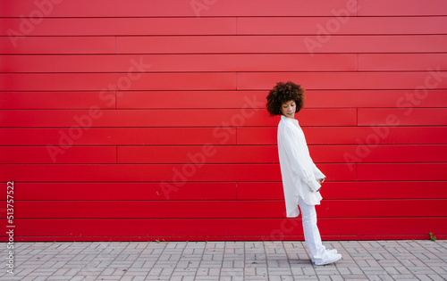 Young woman leaning backward by red wall
