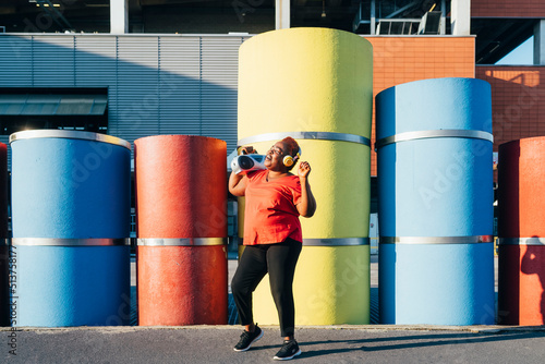 Happy woman carrying boom box radio on shoulder enjoying music photo