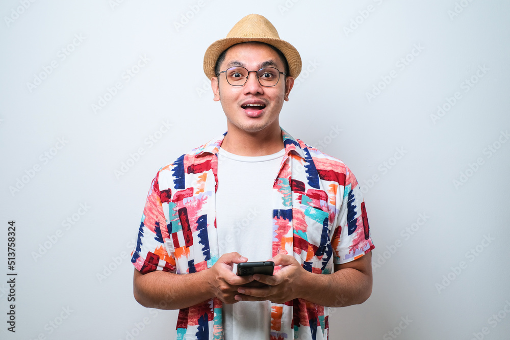 Young asian man showing amazed and surpirsed face expression while looking to the mobile phone screen Young asian man showing amazed and surpirsed face expression while looking to the mobile phone screen