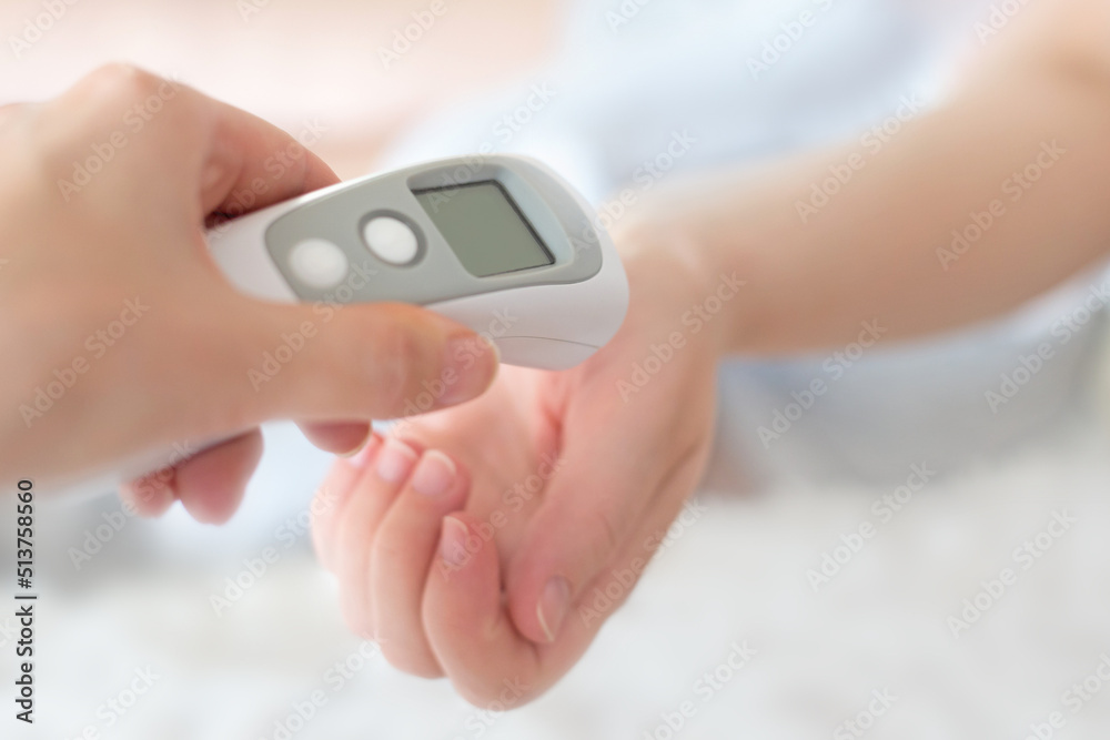 A woman's hand applies an infrared thermometer to measure body temperature A woman's hand applies an infrared thermometer to measure body temperature