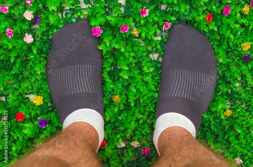 male hairy legs in short socks on artificial green grass, top view
