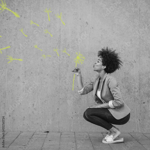 Crouching woman blowing painted blow ball flower photo