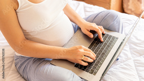 Pregnant computer. Pregnant woman holding digital laptop. Mobile pregnancy online maternity application. Concept of pregnancy, maternity, expectation for baby birth.