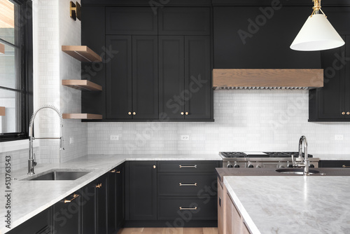 Εκτύπωση καμβά A luxury kitchen with black cabinets, granite counter top, tiled backsplash, stainless steel appliances, and chrome faucets