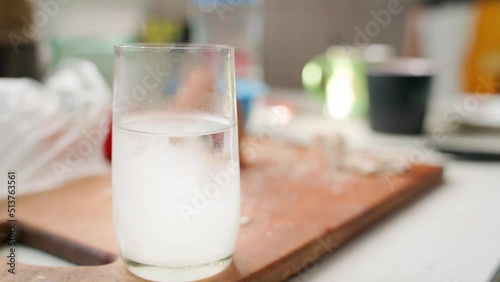 White powder is poured into a transparent glass beaker with water against the background of a feast. Hangover cure in soluble form photo