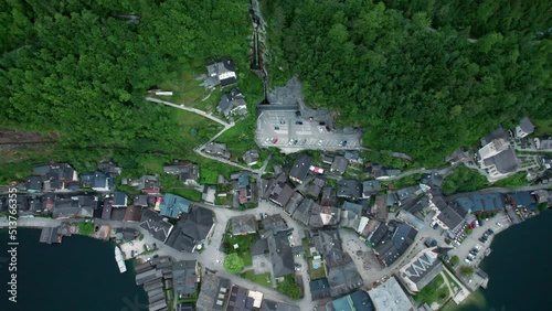Aerial moving from above the parking in mountain while tilting up the camera opening the view of Hallstatt Waterfall.