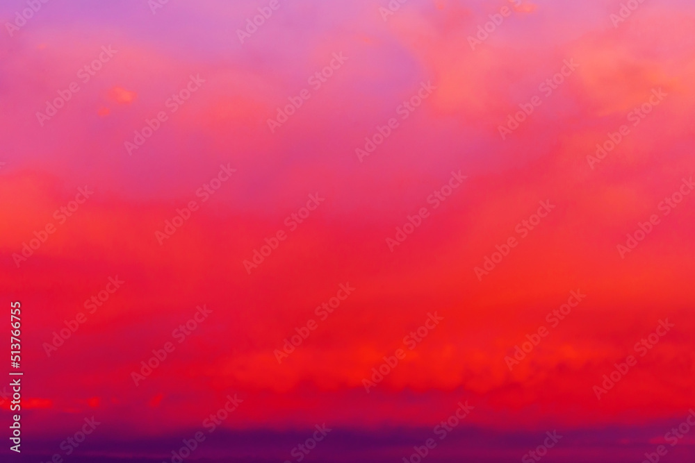 Fototapeta premium Clouds illuminated by the setting sun. Red sunset in the evening sky. Colorful dramatic view with red and purple clouds.