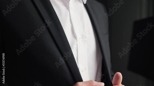 A man stands in front of a window and going to a business meeting. Close up view of man adjusts his suit. Businessman put suit on during morning routine at home, preparing to go to work.