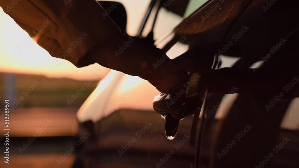 Close-up of young womans hand opens door of red car at sunset. Cinematic slow motion footage with rays of the setting sun. Girl driver, lifestyle, travel Close-up of young womans hand opens door of red car at sunset. Cinematic slow motion footage with rays of the setting sun. Girl driver, lifestyle, travel