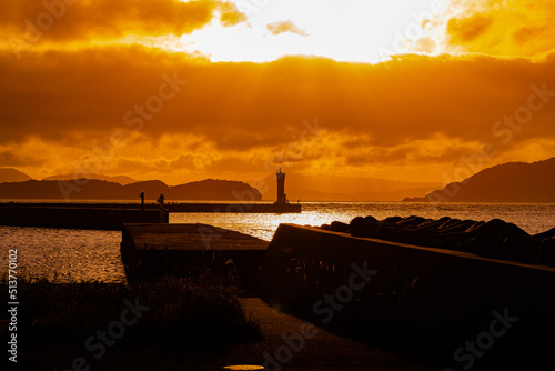 夕日に照らされた防波堤の灯台