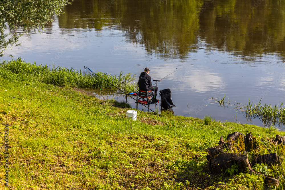 Fisherman sitting by the river on sunny day Fisherman sitting by the river on sunny day