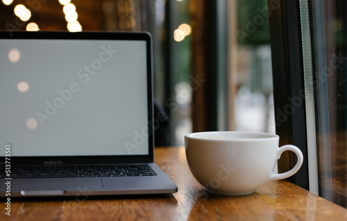 a cup of coffee and a laptop on a table in a coffee shop