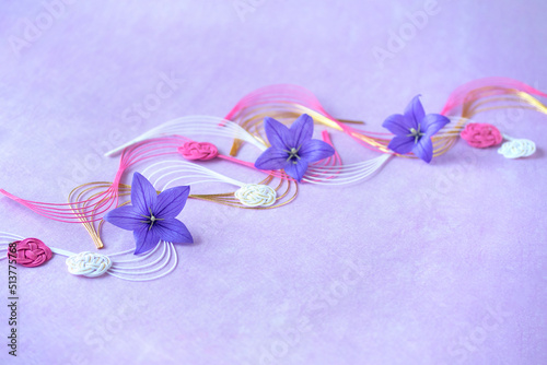 キキョウの花と流れ水引と花型水引のデザイン（薄紫の背景）