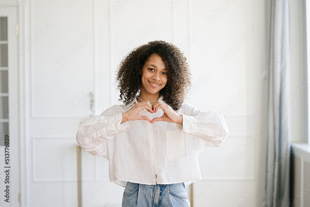 Beautiful nice pretty African american girl with her brunette curly hair she show heart symbol Beautiful nice pretty African american girl with her brunette curly hair she show heart symbol