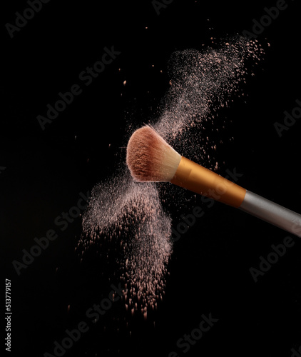 Make up brush with cosmetic powder splash, over black background. Splash image photo