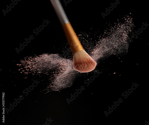 Фотография Make up brush with cosmetic powder splash, over black background