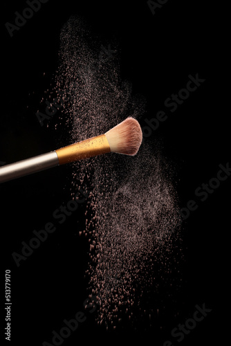 Make up brush with cosmetic powder splash, over black background. Splash image photo