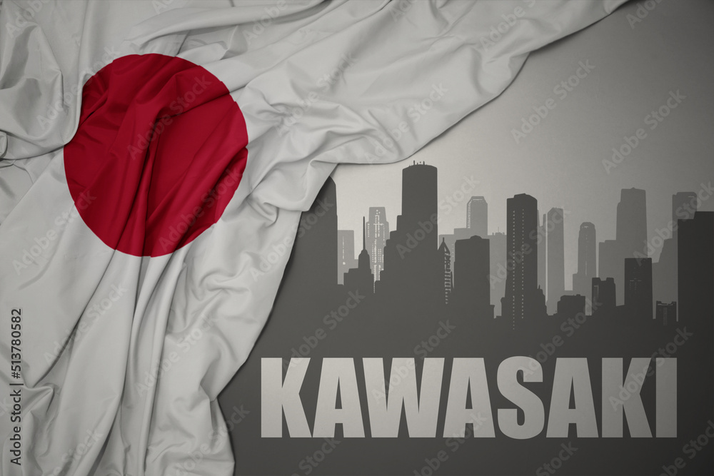 abstract silhouette of the city with text Kawasaki near waving national flag of japan on a gray background.