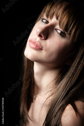 In the dark, confidence. A confident look on the face of a beautiful young model picked out of the darkness.