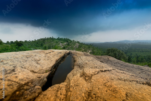 Mayur Paharh is a small hill of Purulia., West Bengal, India. The beautiful rocks stored rain water below , with blue stormy clouds in the background signalling rain is approaching. Monsoon season. photo