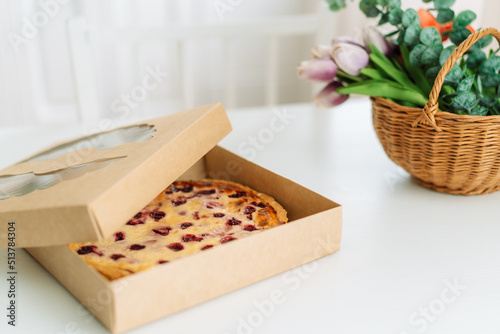 An open box with berry pie stands on white table.
