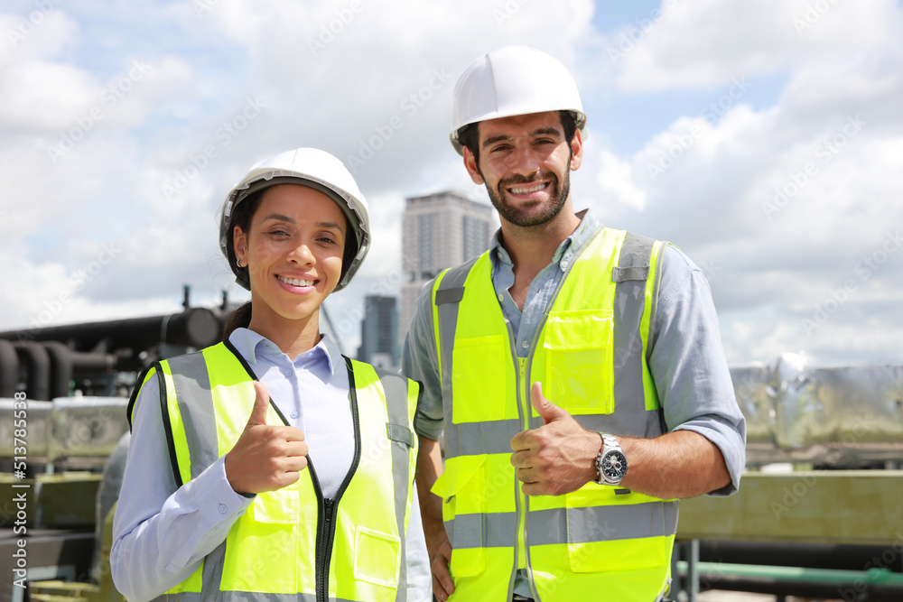 Portrait colleage male and femal engineer with yellow safety vest and white hard hat work on roof top of building , Close up system engineer with Thump up express good job or job done . Portrait colleage male and femal engineer with yellow safety vest and white hard hat work on roof top of building , Close up system engineer with Thump up express good job or job done .