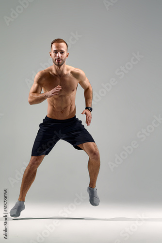 In jump. Caucasian professional sportsman training isolated on white studio background. Muscular, sportive man practicing. Copyspace. Concept of action, motion, youth, healthy lifestyle.