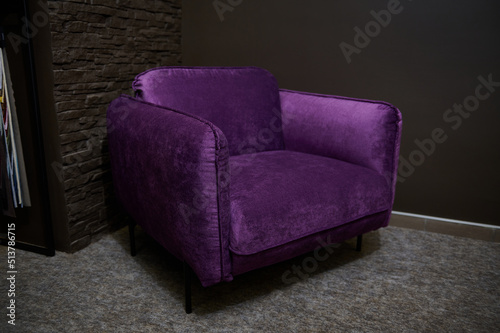 An exhibition of a stylish comfortable purple velour armchair for sale in a furniture design showroom. Upholstered furniture store, home design concept © Taras Grebinets