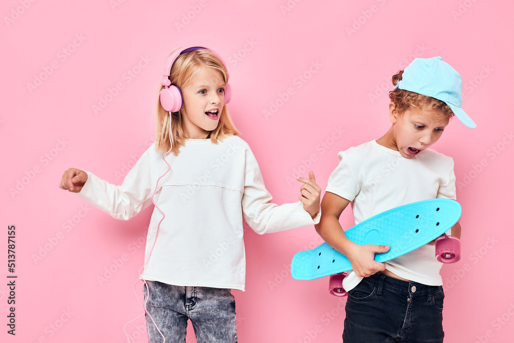 Portrait of two young smiling kids smiling and listening to music in headphones pink color background Portrait of two young smiling kids smiling and listening to music in headphones pink color background