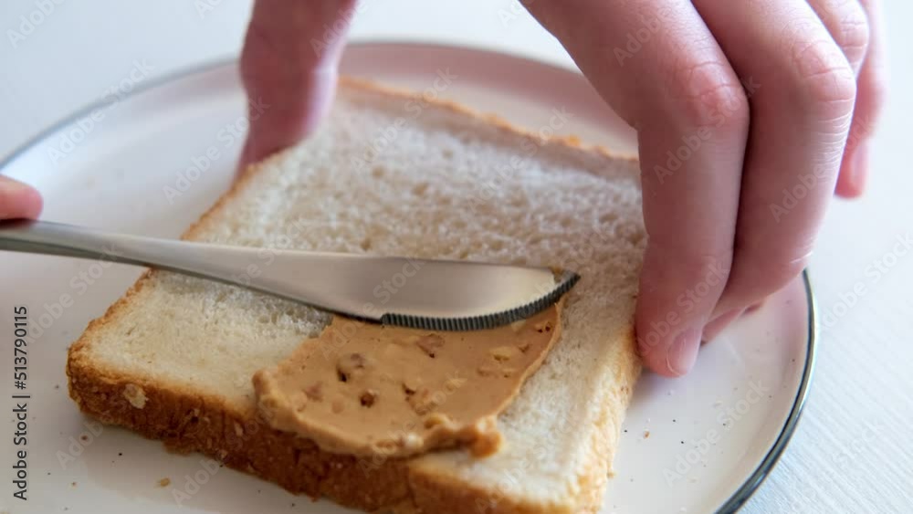 Spreading peanut butter with peanut chunks on bread close-up. Slow motion Spreading peanut butter with peanut chunks on bread close-up. Slow motion