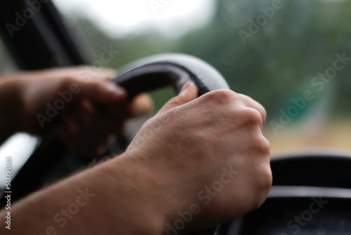 Defocus male hand holding steering wheel. A man's hand handle steering wheel car for driving. Traffic jam, driving car on highway, close up of hands on steering wheel. Closeup. Driver. Out of focus