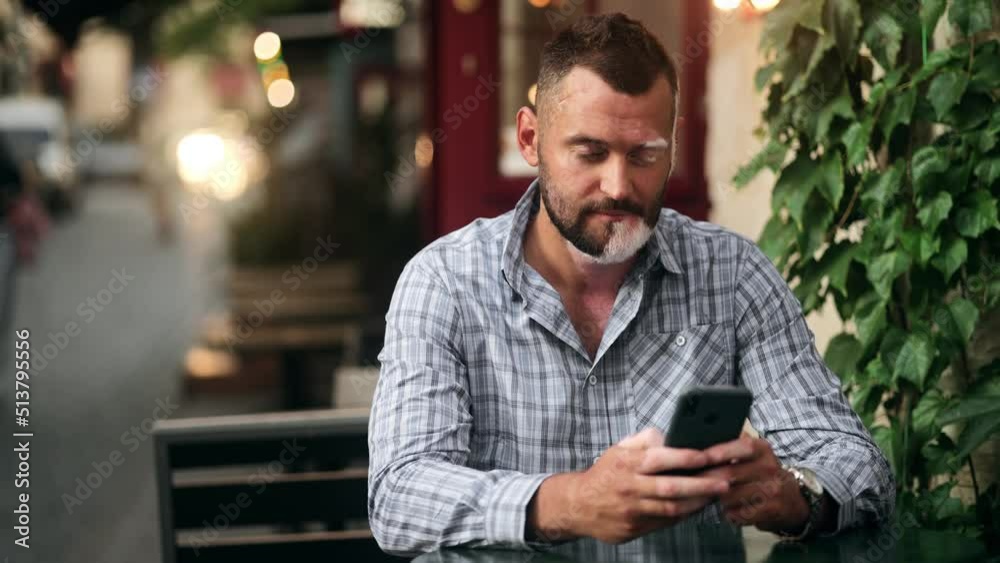 Man with vitiligo pigmentation skin outdoor seating table using smartphone. Modern people. Online shopping. Communication. technology