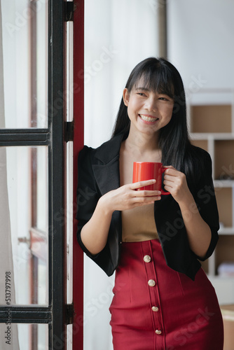 Businesswoman is holding and drinking a cup of coffee in office space