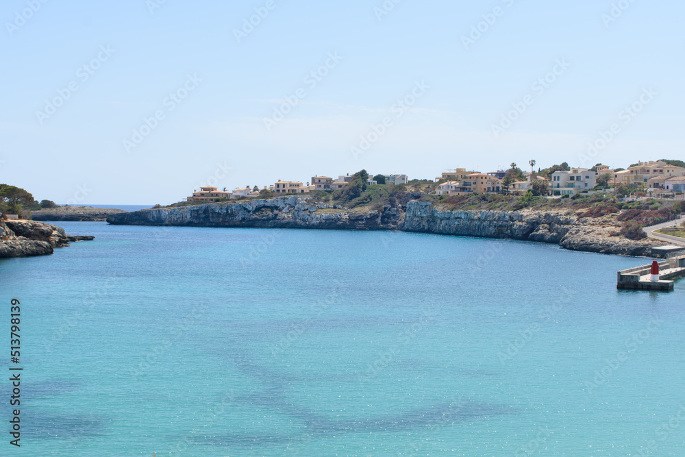Houses on top of the coastal cliffs in Porto Cristo. Calm, turquoise sea water