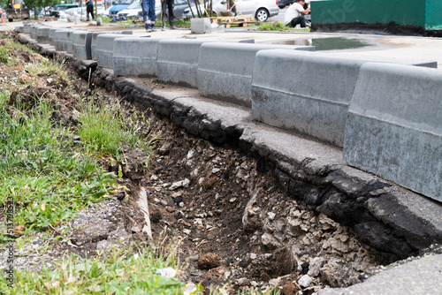 New curbs stand at the edge of the sidewalk. Preparing to repair road