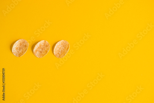 top view of delicious, fried and salty potato chips on yellow