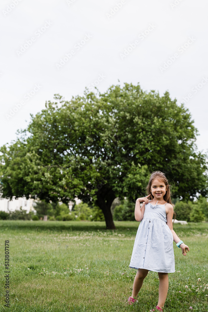 Happy emotional child girl posing outside in the green park. Fashion kid. Smiling toodler girl walking in park. Happy emotional child girl posing outside in the green park. Fashion kid. Smiling toodler girl walking in park.