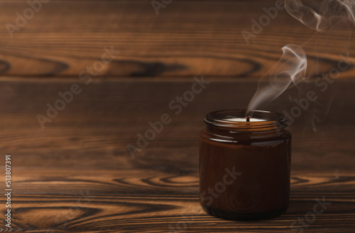 Smoldering candle wick and smoke on brown texture wood.winter home decor.Soy ecological candle.Home and interior decoration.Place for text.Copy space.