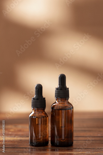 Nature cosmetic in glass bottles and shadow on beige background. Face and body care spa concept. Hyaluronic acid oil, serum with collagen and peptides skin care product