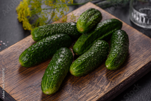 Delicious fresh cucumbers with garlic, salt, spices and herbs on a wooden cutting board