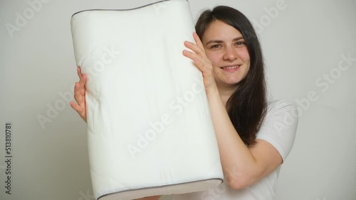 A woman compresses an orthopedic pillow, the pillow takes its former shape photo