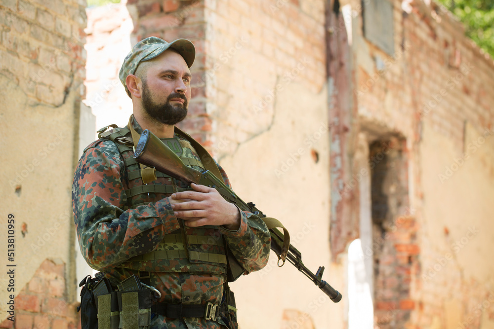 military man with a weapon near a destroyed building military man with a weapon near a destroyed building
