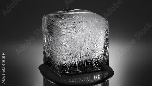 Melting ice cube, water flowing to foreground (viewer). Long version. 