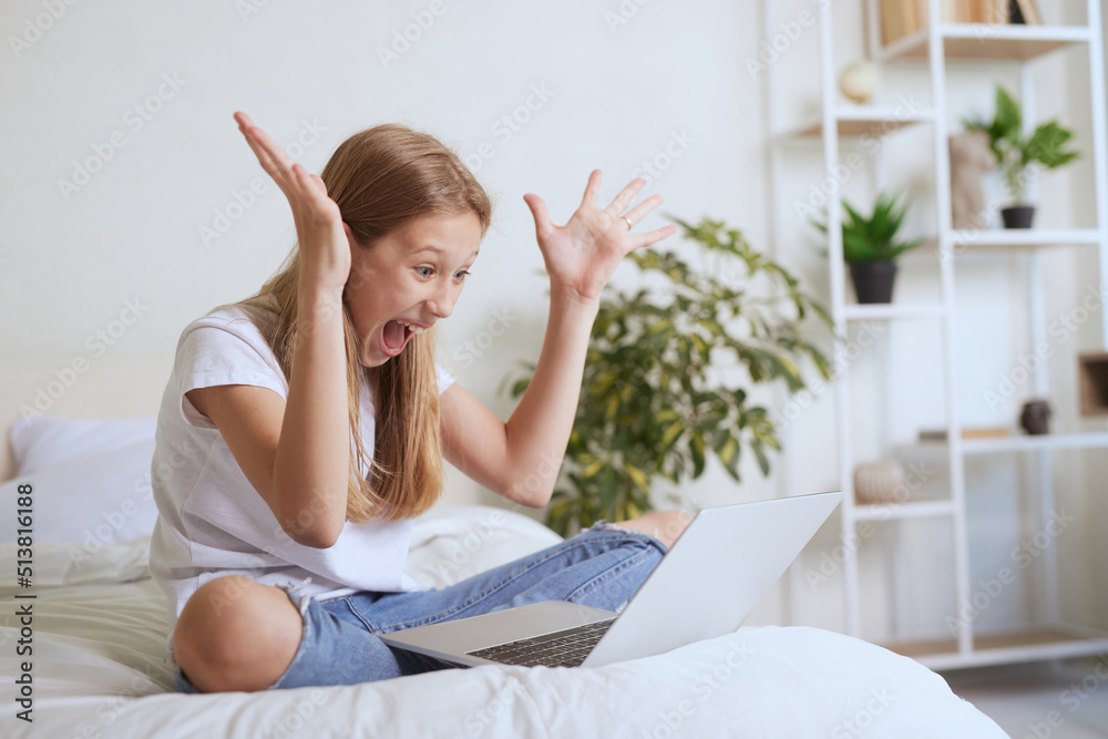 Young girl rejoices from message online on laptop Young girl rejoices from message online on laptop