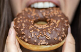 young woman eating donut close up.unhealthy eating concept,weight gain,fat,sugar.tasty delicious dessert glazed with chocolate