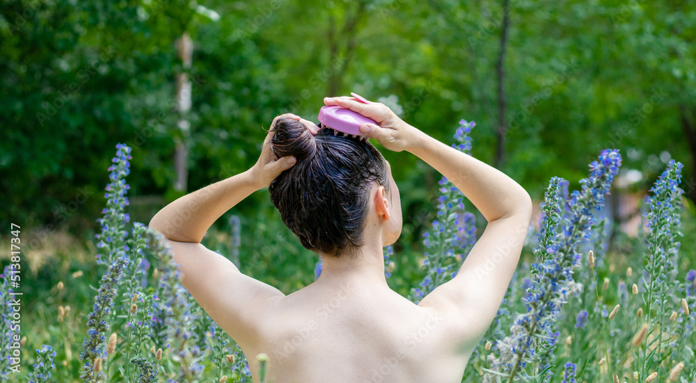 hair growth stimulating, scalp massage.woman in garden,green grass background using  pink scalp massager shampoo brush with silicone,flexible bristels.hair care,head relaxation. - obrazy, fototapety, plakaty 