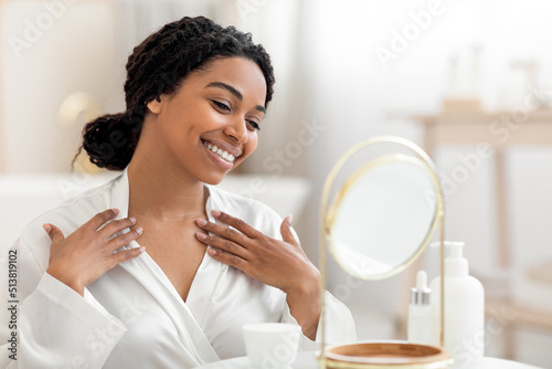 Принти на полотні Beautiful black woman looking in mirror and touching decollete zone