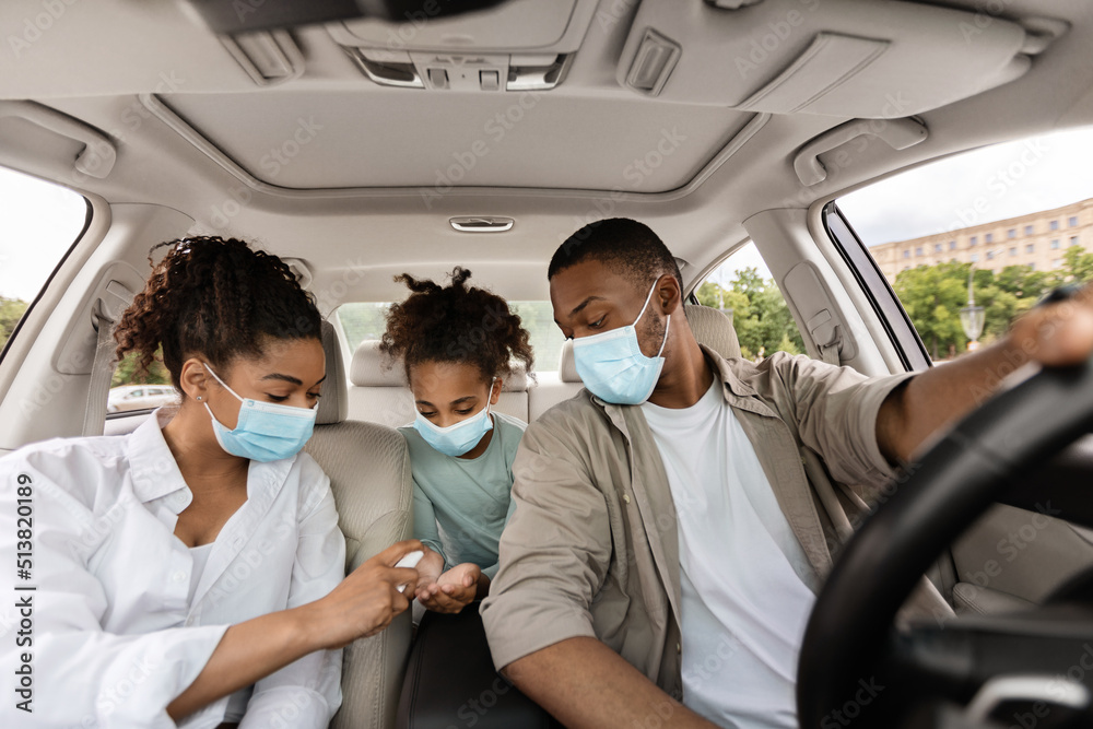 Black Family Spraying Sanitizer On Hands In Car Black Family Spraying Sanitizer On Hands In Car