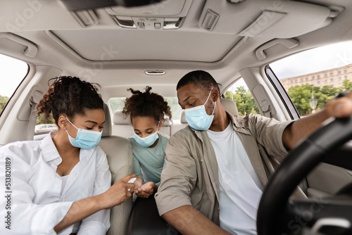 Black Family Spraying Sanitizer On Hands In Car