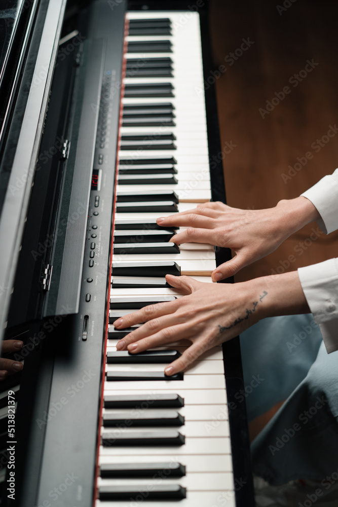Fototapeta premium refined woman pianist plays the piano with thin fingers, sensually plays a musical instrument